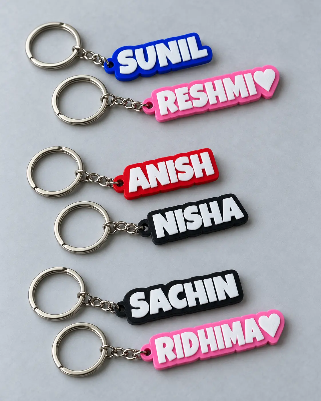 Personalized name keyrings in blue, pink, red, and black, with white lettering