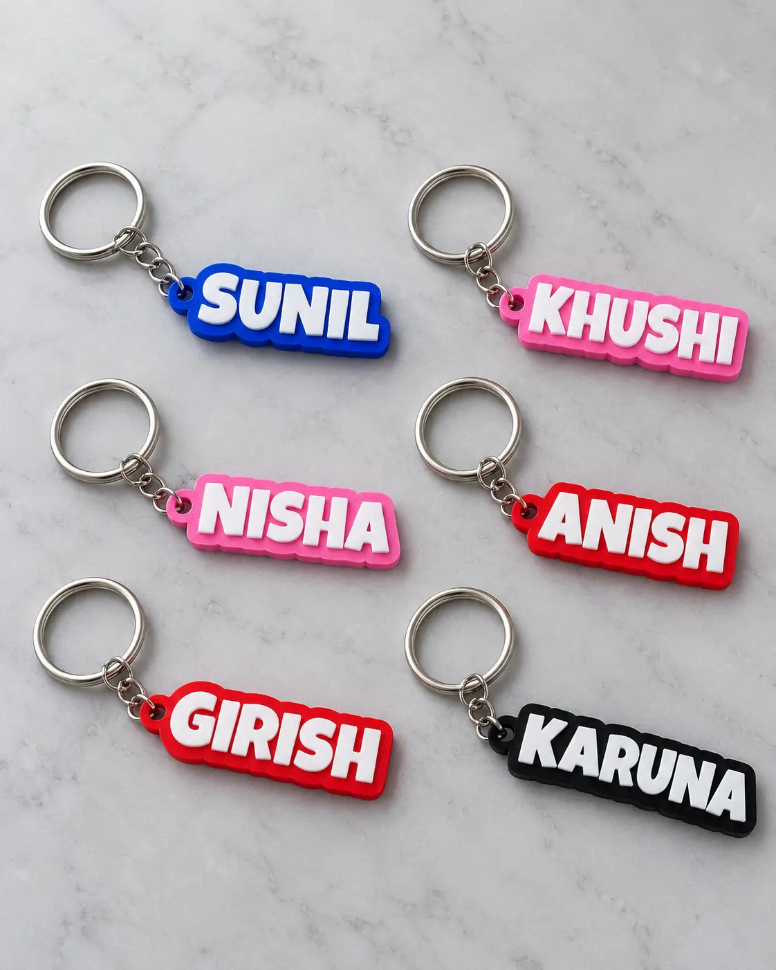 Six colourful name keyrings arranged on a light surface