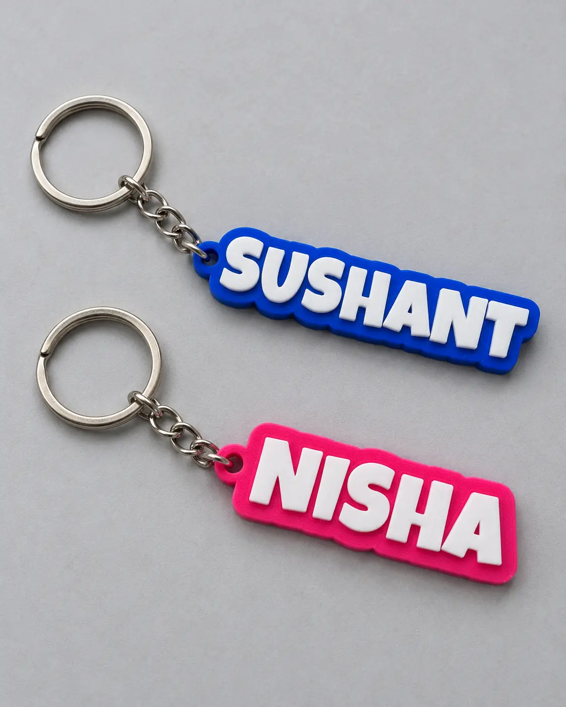 Blue Sushant and pink Nisha name keyrings with metal rings and chains