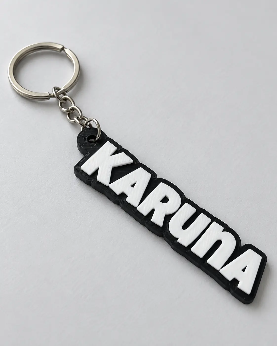 A black Karuna name keyring with raised white lettering